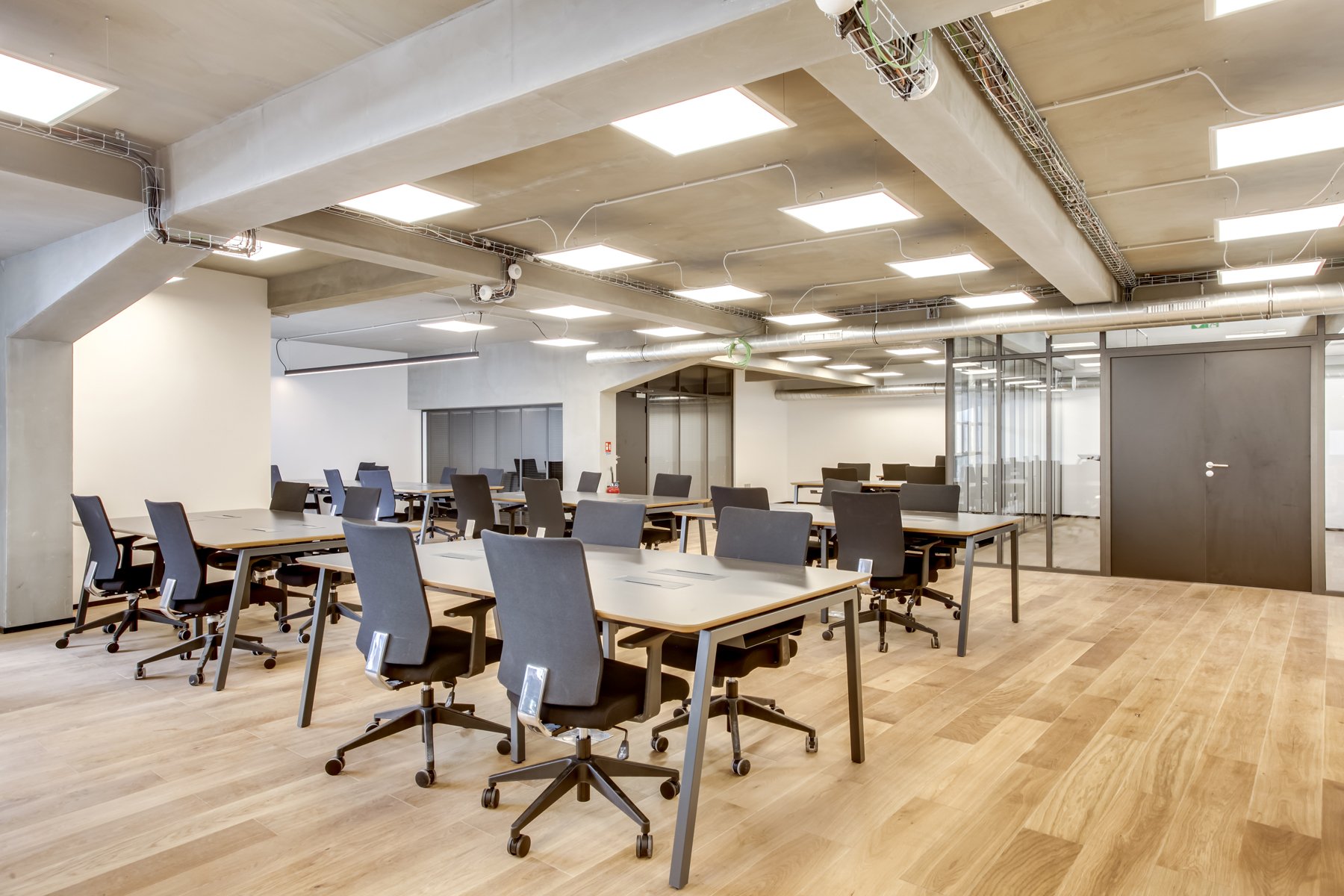 Plateau de bureaux en open space avec îlots de postes, cloisons acoustiques basses et grandes baies vitrées